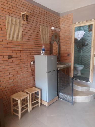 a kitchen with a refrigerator and a brick wall at Gite Rahhaoui Simo in Kasba des Aït Moussa