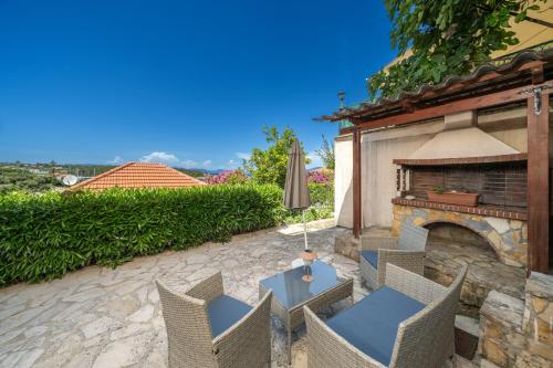 a patio with a table and chairs and a fireplace at Tassos Cottage Fiskardo in Fiskardo