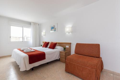 a bedroom with a bed and a chair at Rentalmar Pineda Suites in La Pineda