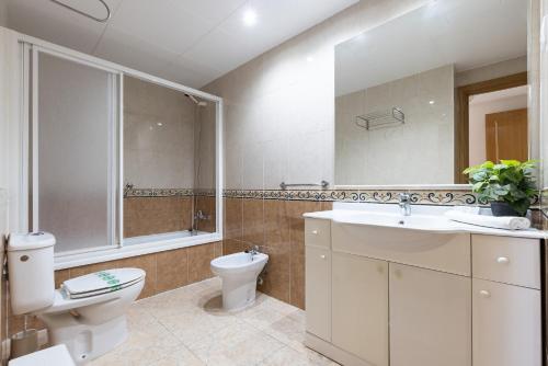 a white bathroom with a toilet and a sink at Rentalmar Pineda Suites in La Pineda