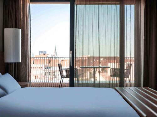 a bedroom with a bed and a view of a balcony at Pullman Basel Europe in Basel