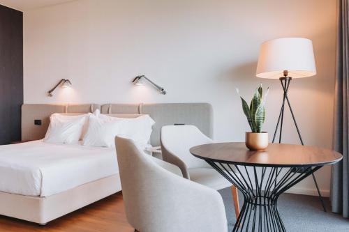 a bedroom with a bed and a table and a chair at Hotel Flor De Sal by The Editory in Viana do Castelo