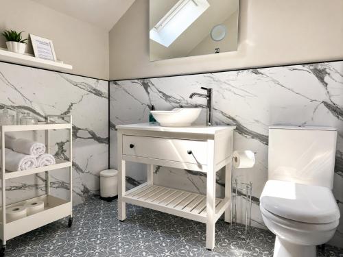 a white bathroom with a sink and a toilet at Ardvreck House in Ullapool