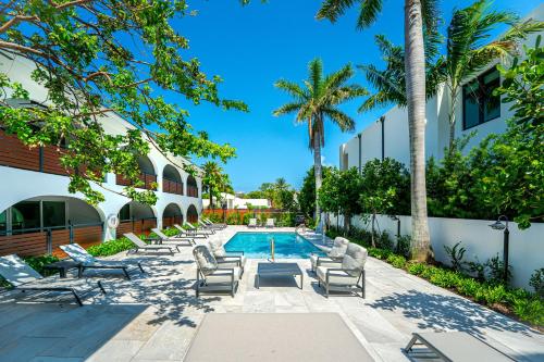 a pool with lounge chairs and palm trees next to a building at Casa Coral - Boca Poolside Escape in Boca Raton