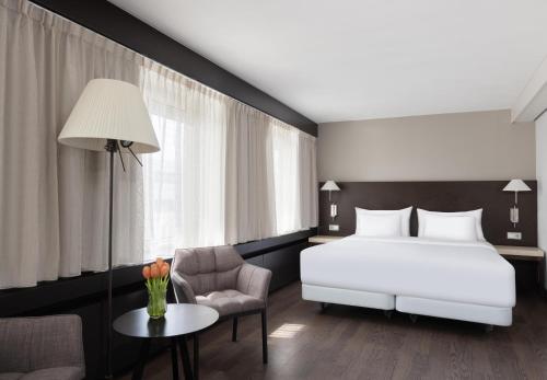 a bedroom with a bed and a chair and a table at NH Noordwijk Conference Centre Leeuwenhorst in Noordwijkerhout