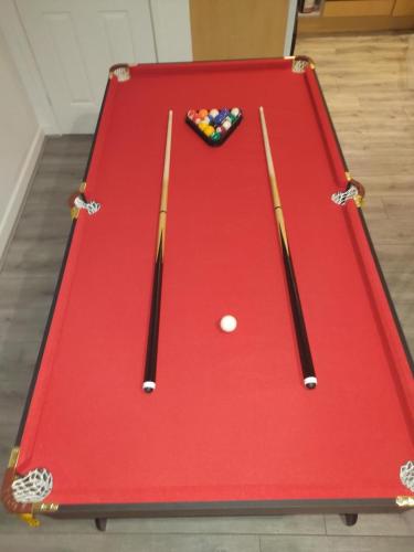 a red snooker table with two cue sticks and a ball at Luton Grove in Liverpool