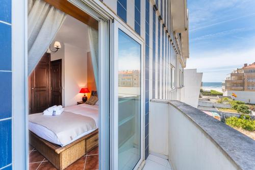 a balcony with a bed and a view of the ocean at Salt & Sand Costa Nova Beach in Costa Nova