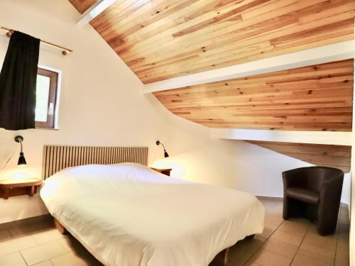 a bedroom with a white bed and wooden ceilings at Le Noyer in Lierneux