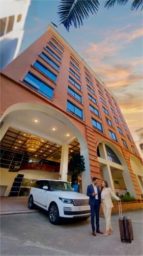 a bride and groom standing in front of a building with a car at Grand Mostafa Hotel in Sylhet