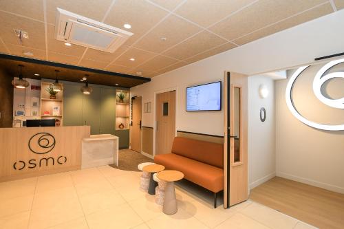 a waiting room with a couch and two stools at The Originals Boutique, Osmo Hôtel, Rennes Sud Chantepie in Chantepie
