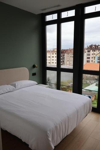 a bedroom with a large white bed and large windows at MoV Flexliving in Oviedo