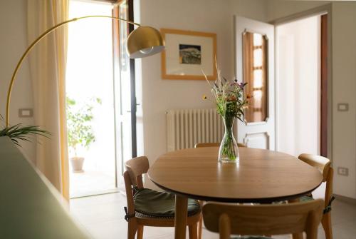 a dining room table with a vase of flowers on it at Sky & Vineyards - Melograno - in La Morra
