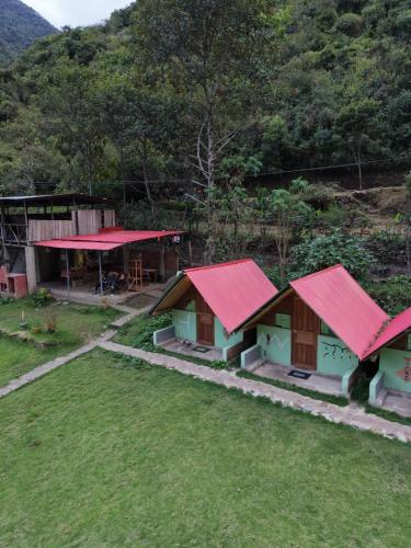 a group of houses with red roofs in a field at Pablito Hostel Challhuay in Colcapampa