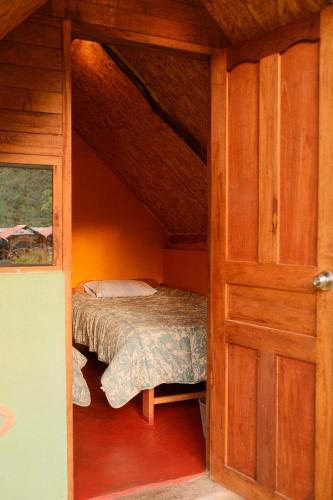 a small bedroom with a bed and a wooden door at Pablito Hostel Challhuay in Colcapampa