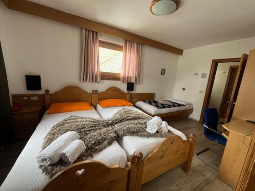a bedroom with a large bed with towels on it at Albergo Genziana in Bormio