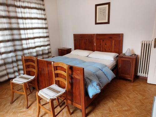 ein Schlafzimmer mit einem Bett und zwei Stühlen in der Unterkunft CasaColdai in Alleghe