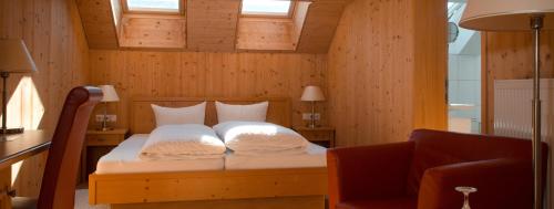 a bedroom with a bed with a chair and two windows at Gasthaus Engel in Bezau
