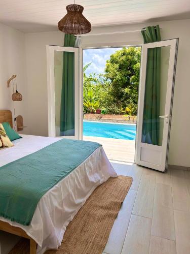 a bedroom with a bed and a sliding glass door at Villa neuve Casa Helena - Piscine privée et jardin - 6 pers - Saint-Esprit - Sud Martinique in Quartier Palmène