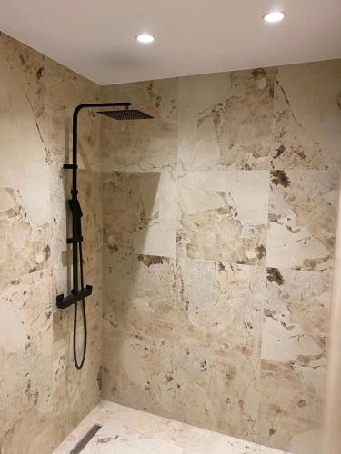 a shower in a bathroom with a stone wall at Luciano Rooms in Ksamil