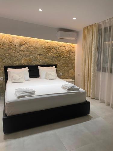 a bedroom with a large bed with a stone wall at Luciano Rooms in Ksamil