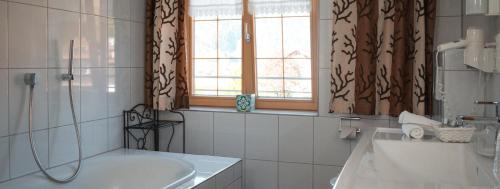 a bathroom with a tub and a sink and a window at Gasthaus Engel in Bezau