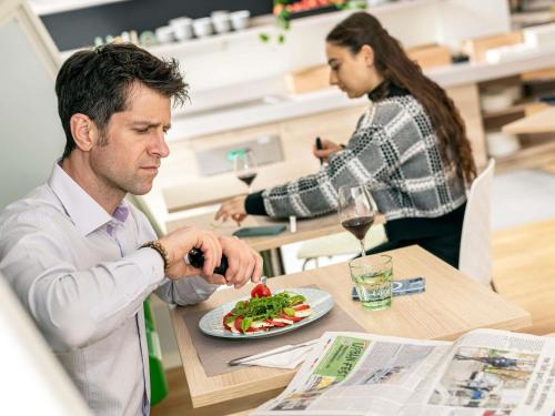 a man sitting at a table with a plate of food at ibis Styles Strasbourg Stade de la Meinau in Strasbourg