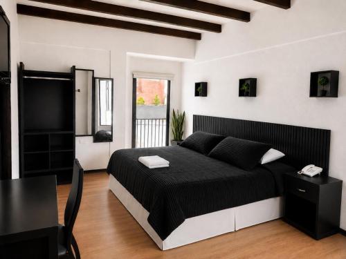 a bedroom with a black and white bed and a table at Hotel Bellavista Quito in Quito