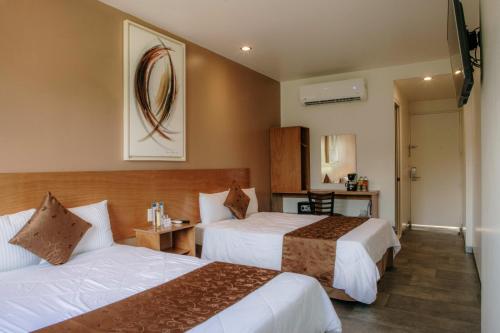 a hotel room with two beds and a table at AM Hotel y Plaza in Santa Cruz Huatulco