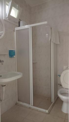 a bathroom with a shower and a toilet and a sink at Marigold Otel in Çeşme