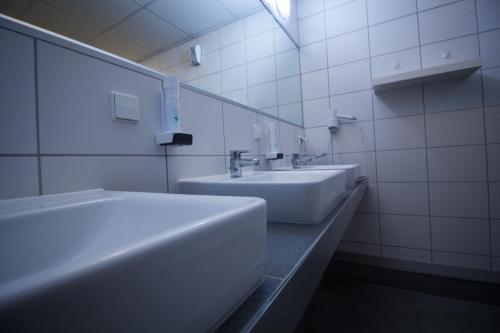 a white bathroom with two sinks and a mirror at Hostel Gästehaus Kaiserpassage- Ihr Cityhostel in Karlsruhe