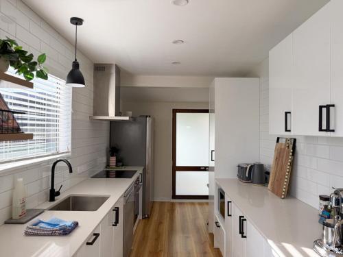a kitchen with white counters and a stainless steel refrigerator at Waikanae Beach Abode in Waikanae