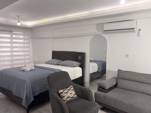 a bedroom with two beds and a chair and a couch at Saklıkonak Otel in Isparta