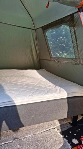a bed in a green tent with a window at B&B RhinoSauna in Vihti
