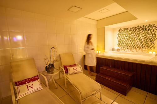 a woman standing in a bathroom with two chairs and a tub at Royal Collection Paulista in São Paulo