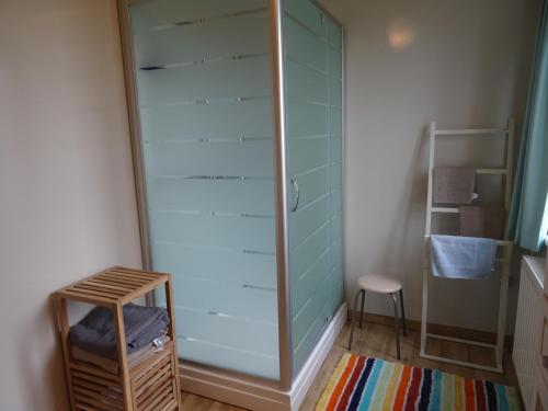 a glass shower in a room with a stool at Brouckmolen in Alveringem