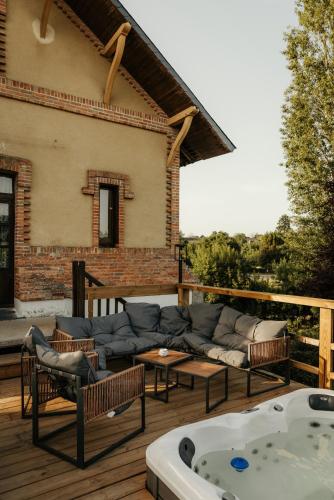 a patio with a couch and a hot tub at Moulin de Micheline - Jacuzzi - Vue Exceptionnelle in Bourg-dʼIré