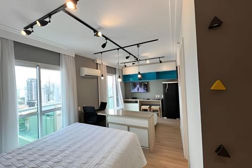 a bedroom with a bed and a desk and a kitchen at Flat Moderno c/ Vista Próx. PUC, Allianz, Pacaembu in São Paulo