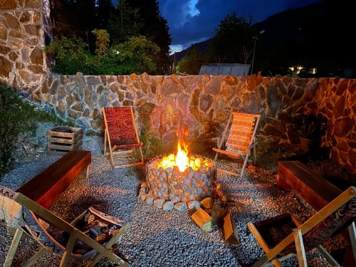 eine Feuerstelle mit zwei Stühlen und einer Steinmauer in der Unterkunft Shgedi Mestia in Mestia