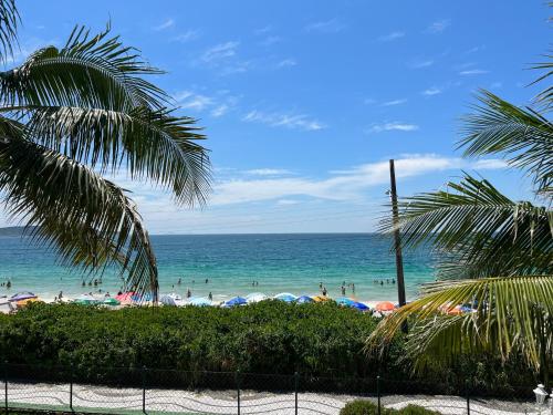 a beach with umbrellas and people in the water at Hotel Vila do Farol in Bombinhas