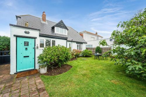 a house with a blue door and a yard at Saltwater, East Wittering in East Wittering