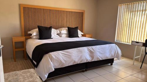 a bedroom with a large bed with black and white sheets at The Pebbles-Unit-1 in Mahikeng
