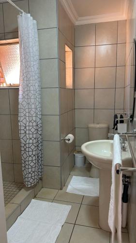 a bathroom with a sink and a toilet and a shower at The Pebbles-Unit-1 in Mahikeng