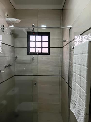 a bathroom with a glass shower and a window at Pousada Brisa da Mata in Londrina