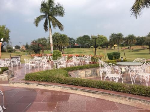 a group of white chairs and a table in a park at Shiva Oasis Resort in Neemrana