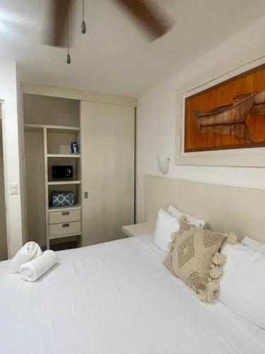a bedroom with a white bed and a painting on the wall at Isla Lorens in Isla Mujeres