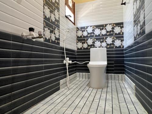 a bathroom with a toilet and black and white stripes at Geetham Homestay in Tiruchirappalli