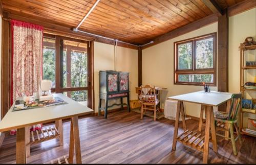 a living room with two tables and chairs and windows at Casa Bosque Encantador in Rancho Queimado