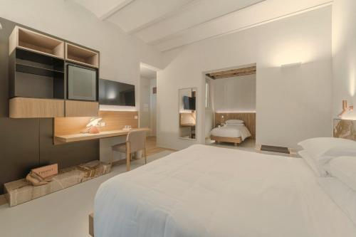 a bedroom with a large white bed and a desk at Albergo Egadi in Favignana