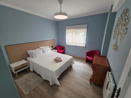 a blue bedroom with a bed and two red chairs at Quinta da Mainça in Coimbra