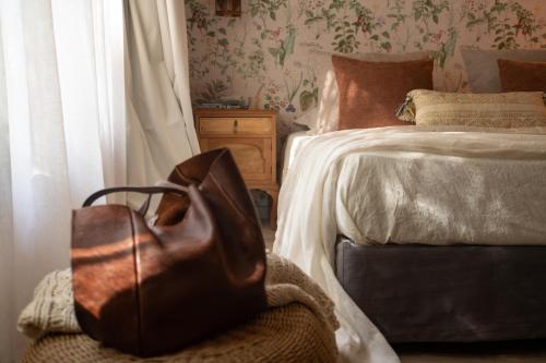 a brown bag sitting on a chair next to a bed at Atelier Petit Hotel in Ciudad Lujan de Cuyo